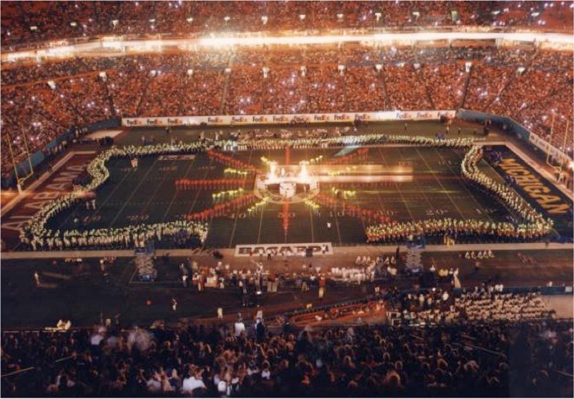 A packed stadium during an elaborate halftime show with bright lights and performers.