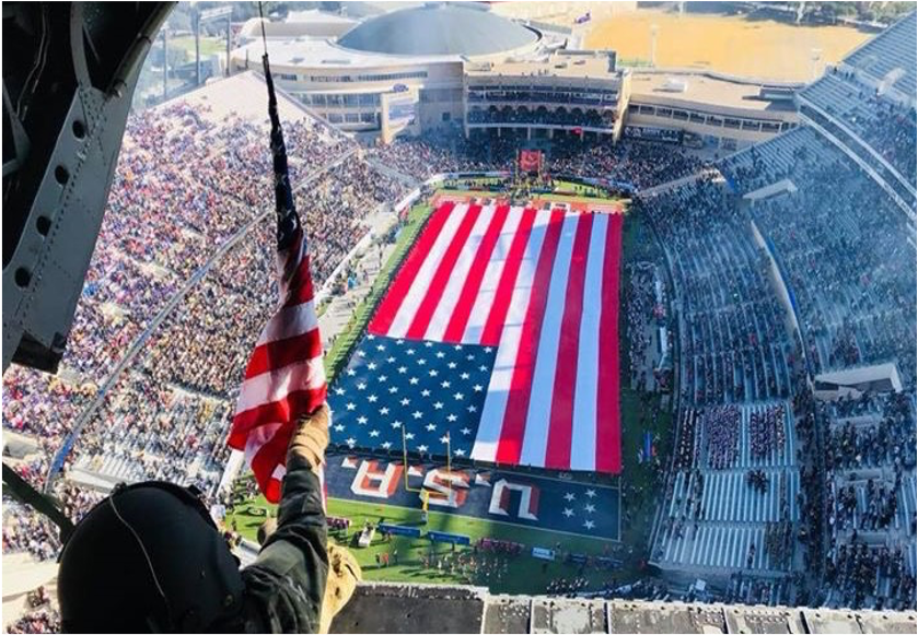 A large American flag displayed at a packed stadium event.