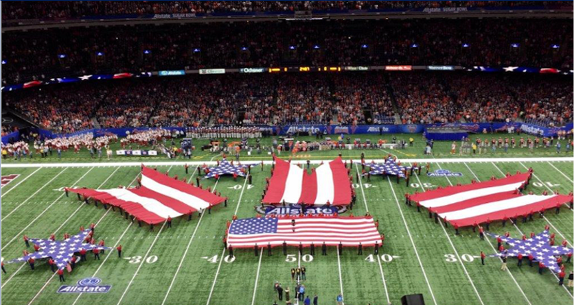 Large American flags displayed on a football field during a stadium event.