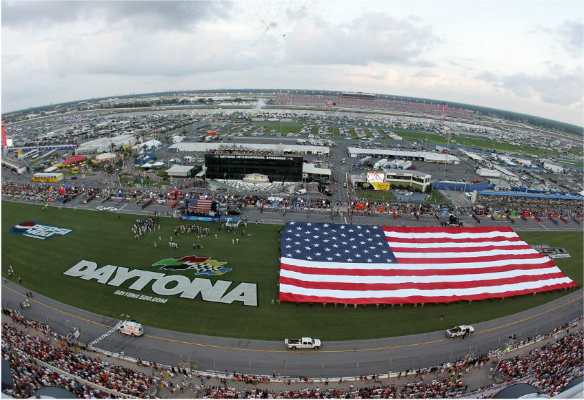 A large American flag displayed at Daytona race track during an event.